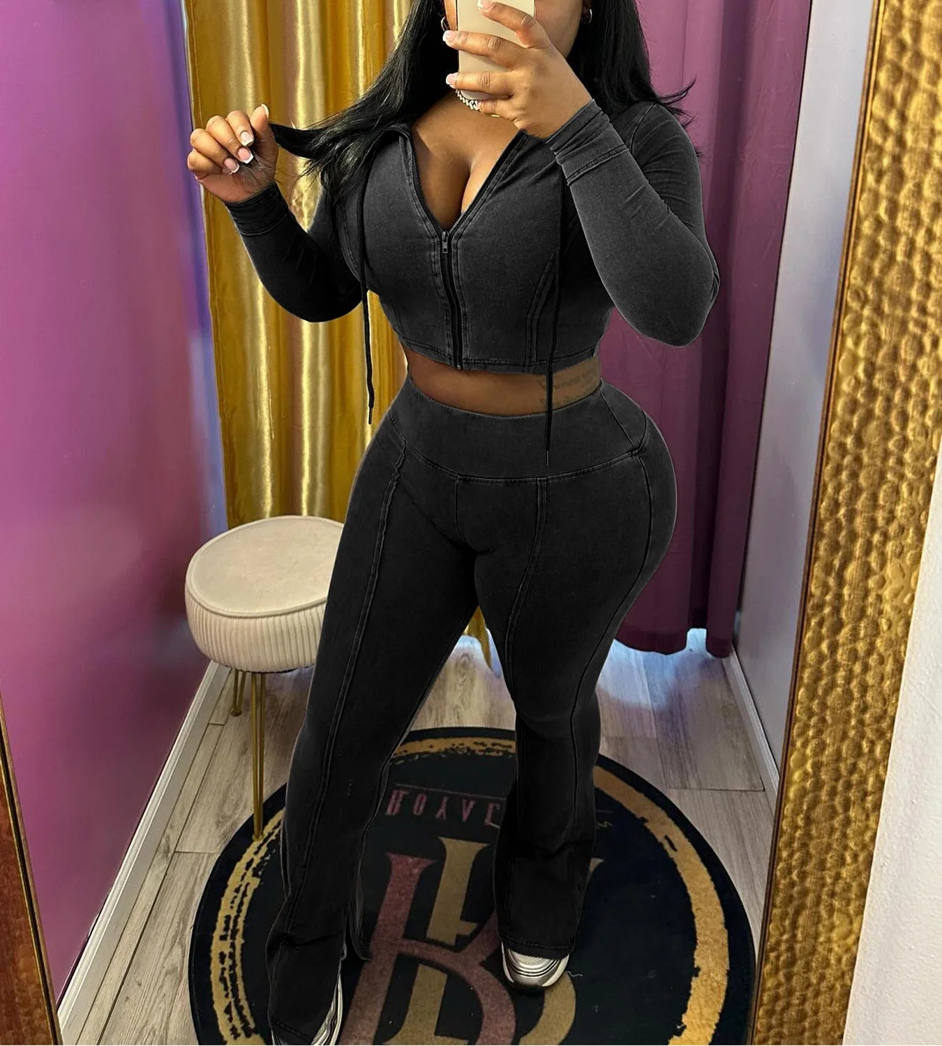 Person wearing a black outfit in a room with pink walls and a gold curtain.