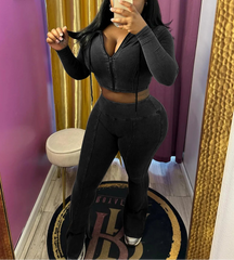 Person wearing a black outfit in a room with pink walls and a gold curtain.