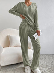 Person wearing a green ribbed sweater and pants set in a living room.