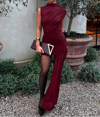 Woman in a burgundy dress holding a clutch outdoors.