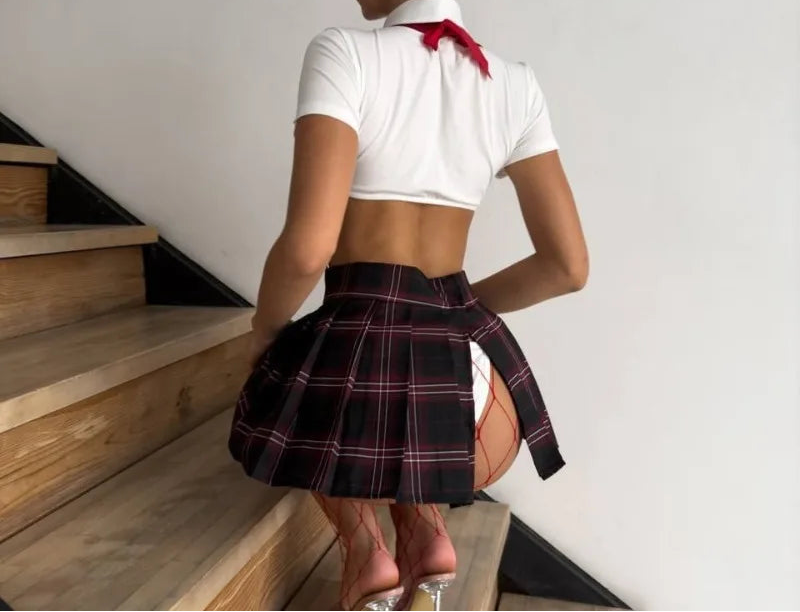 Woman in a white crop top and plaid skirt standing on a staircase.