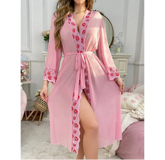 Pink robe with floral lace details worn by a model in a bedroom setting