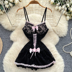 Black lace lingerie set with pink bows on a hanger against a floral and rug background