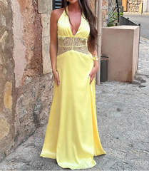 Woman in a yellow dress standing in an outdoor setting with stone walls.