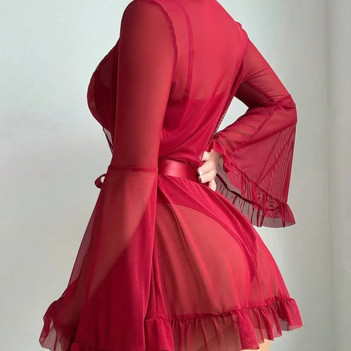 Red dress with sheer sleeves and ruffled hem on a plain background