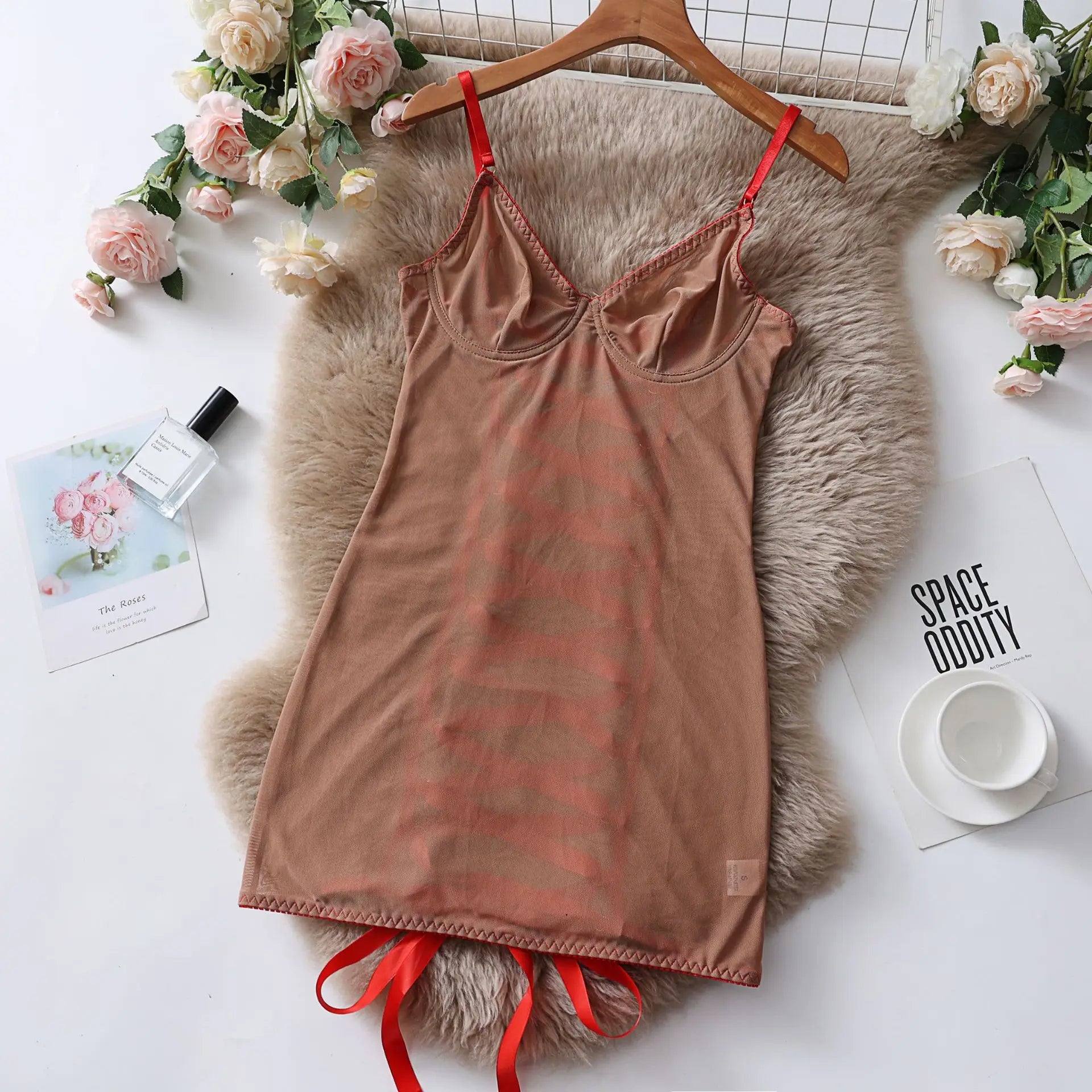 Brown nightgown with red straps on a hanger against a white background with flowers and decor.