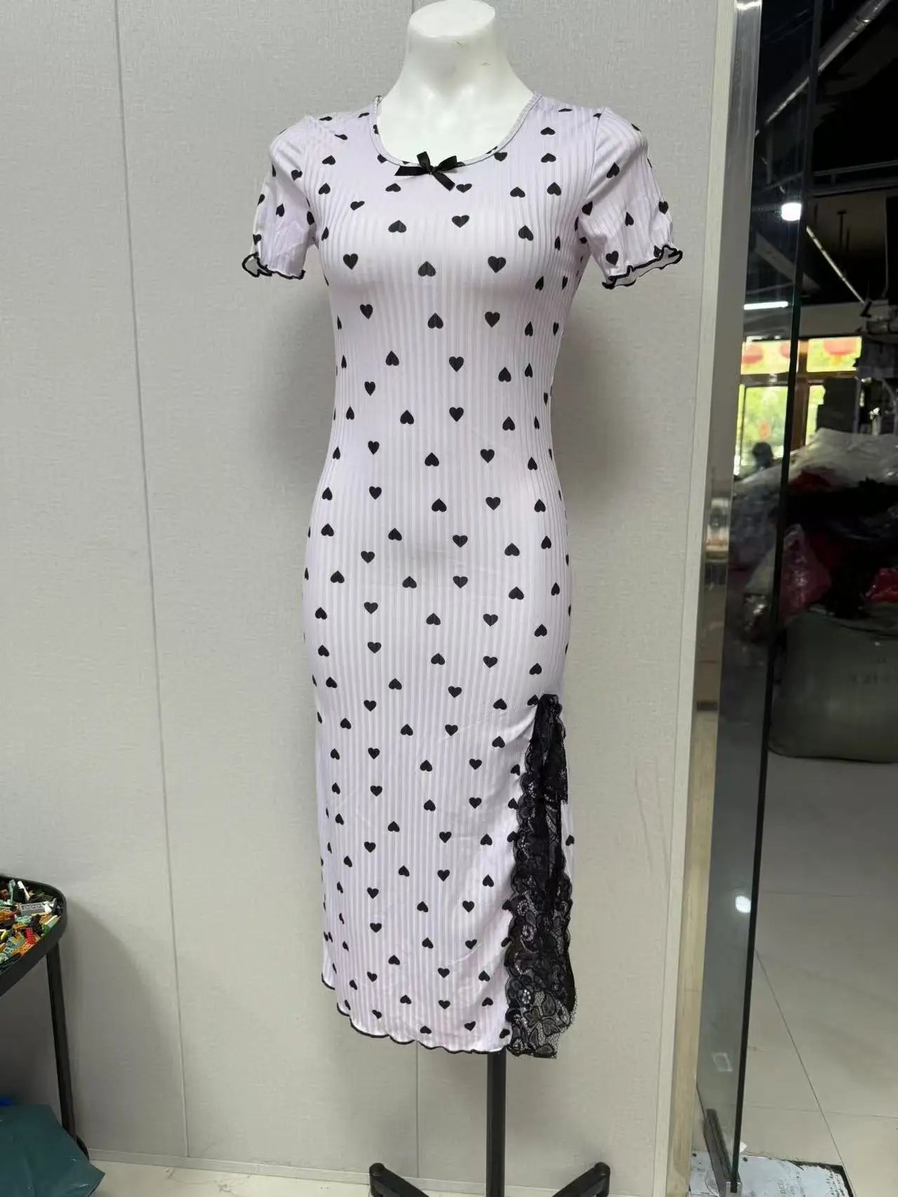 White dress with black heart patterns on a mannequin against a white wall.