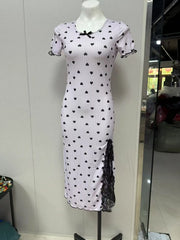 White dress with black heart patterns on a mannequin against a white wall.