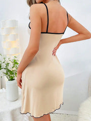 Beige slip dress with black straps worn by a person in a home setting.