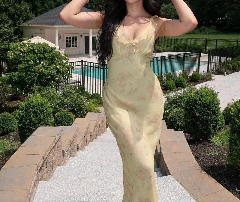 Woman in a yellow dress standing on stone steps with a pool and house in the background