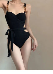 Black swimsuit with gold accents on a neutral background