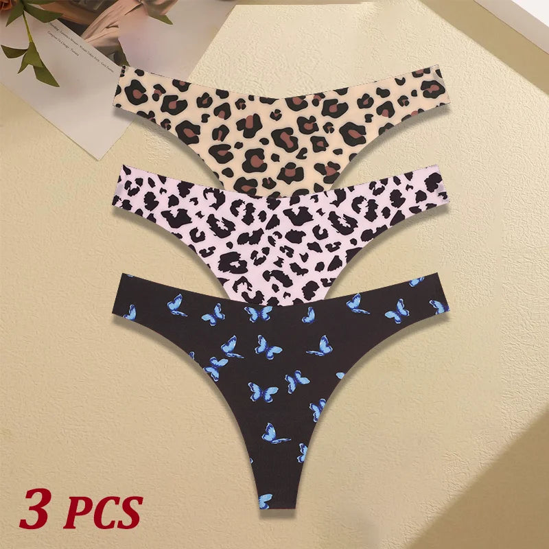Three pairs of leopard print and butterfly patterned underwear on a beige surface.
