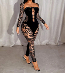 Model wearing a black fishnet outfit with long sleeves and sheer panels against a white curtain background.