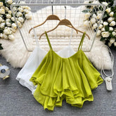 Green ruffled top on a hanger with flowers and a fluffy rug in the background