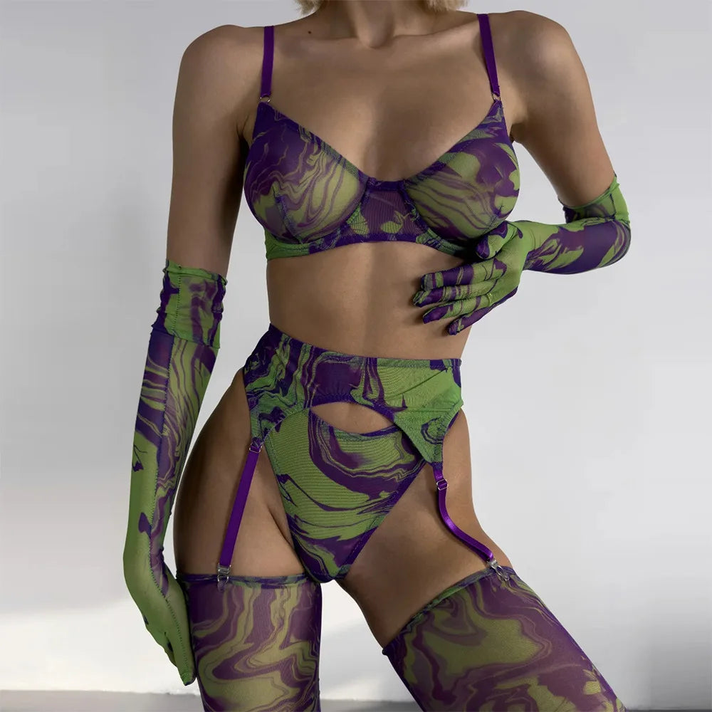 Person wearing a green and purple patterned lingerie set with matching gloves and stockings on a plain background.