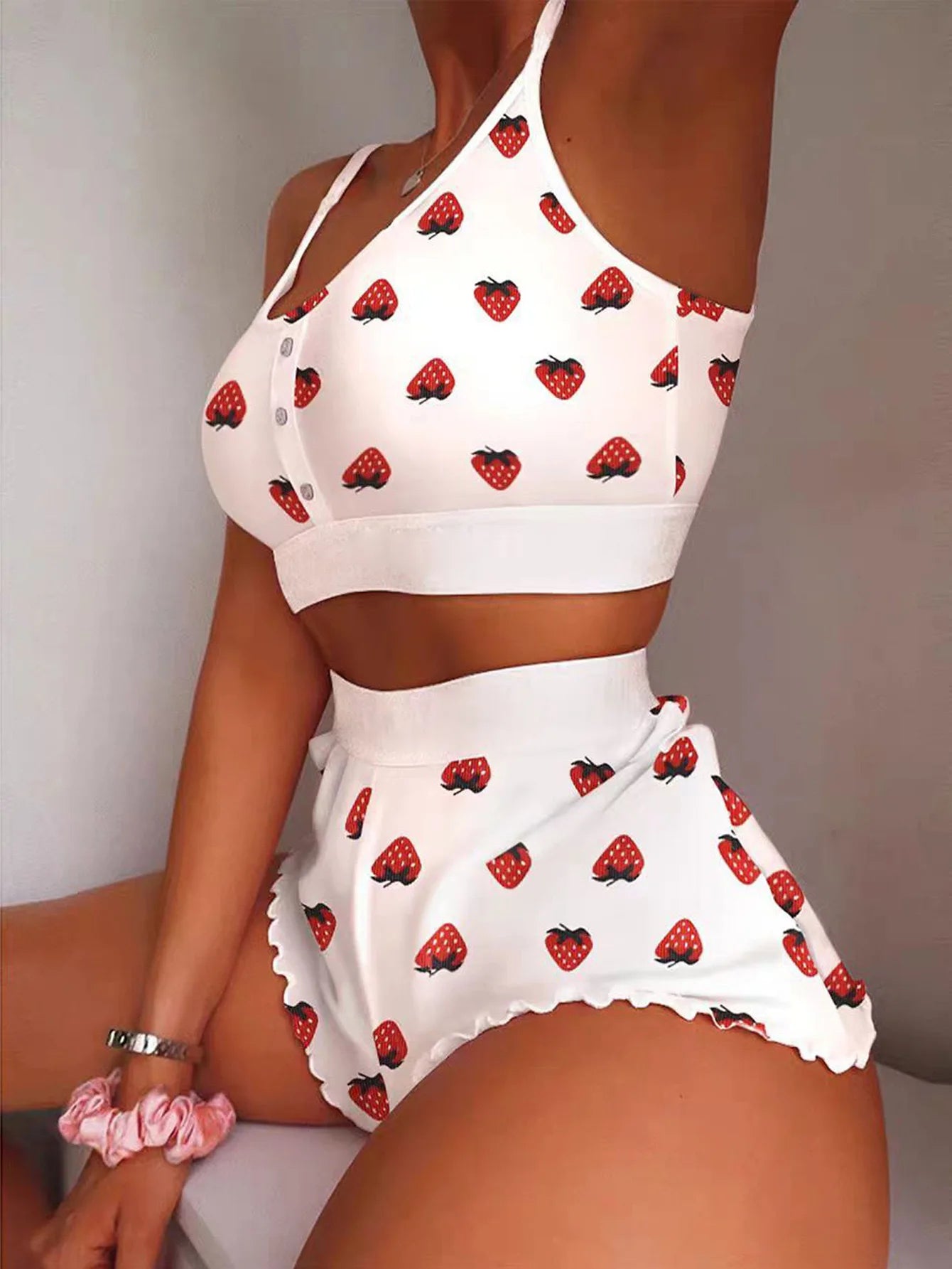 White outfit with red strawberry pattern worn by a person against a neutral background