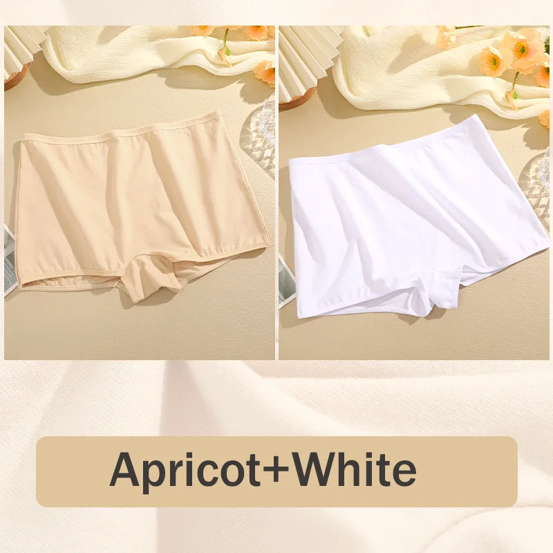 Two pairs of underwear, one apricot and one white, on a beige surface with flowers in the background.
