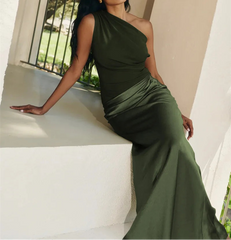 Woman in a green dress sitting on a white ledge with trees in the background