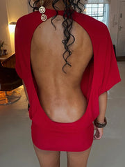 Person wearing a red dress with an open back in a room.