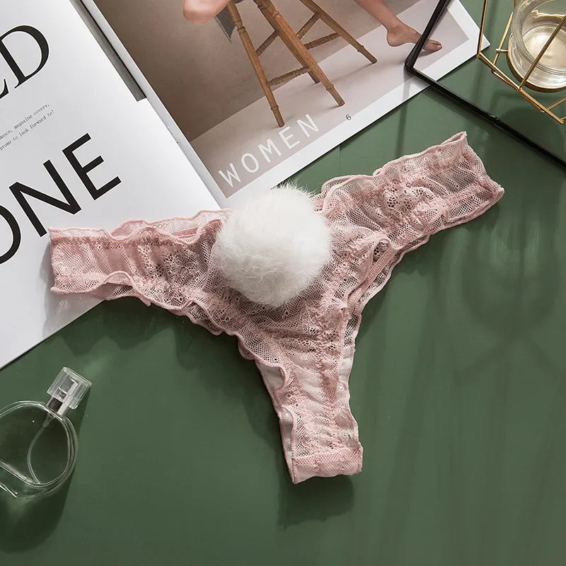Pink lace thong with white fluffy center on a green surface