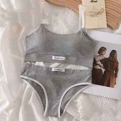 Gray women's underwear set on a white fabric background with a magazine and wooden object.