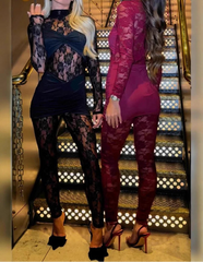 Two women in lace outfits standing on a staircase with decorative lighting.