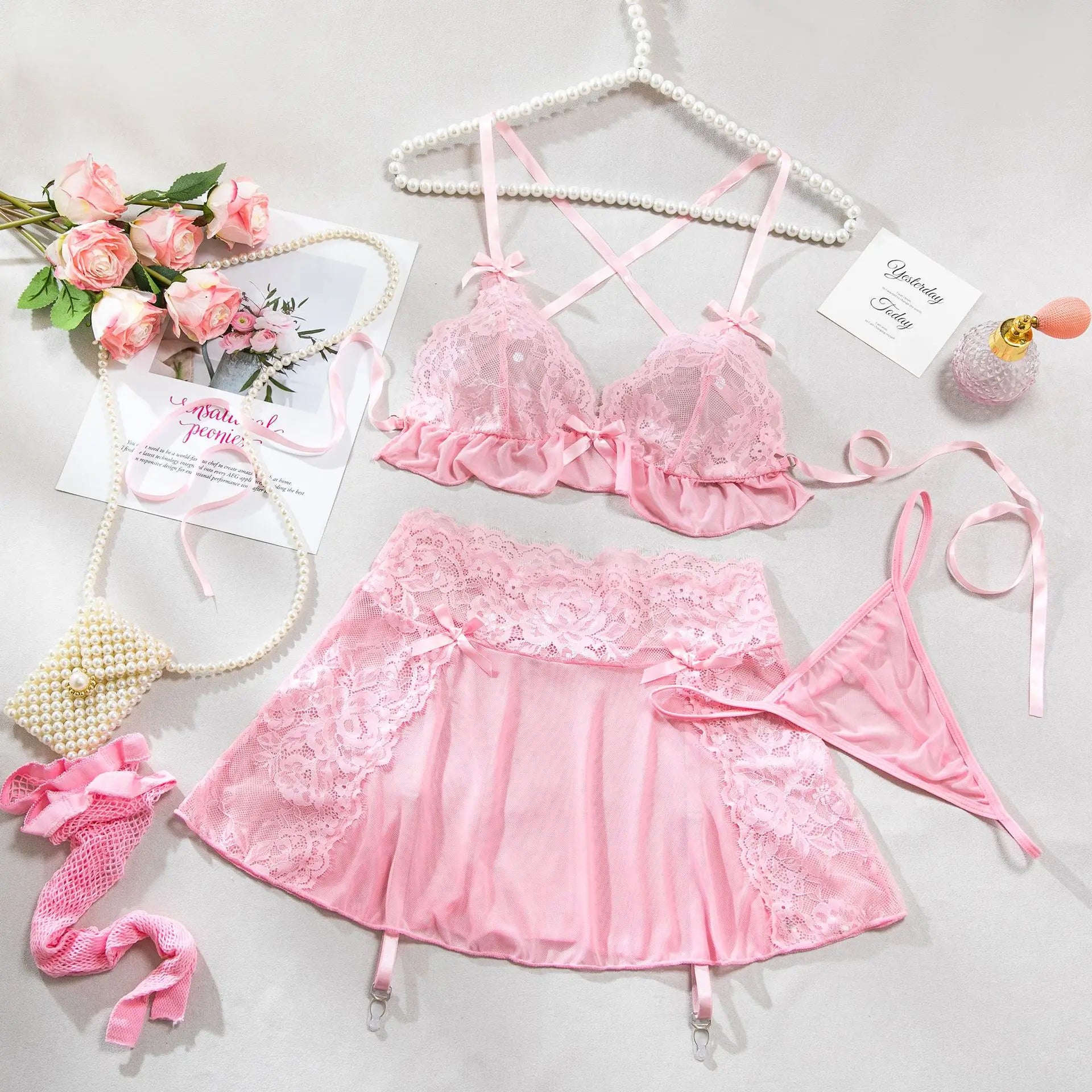 Pink lace lingerie set with accessories on a light gray background