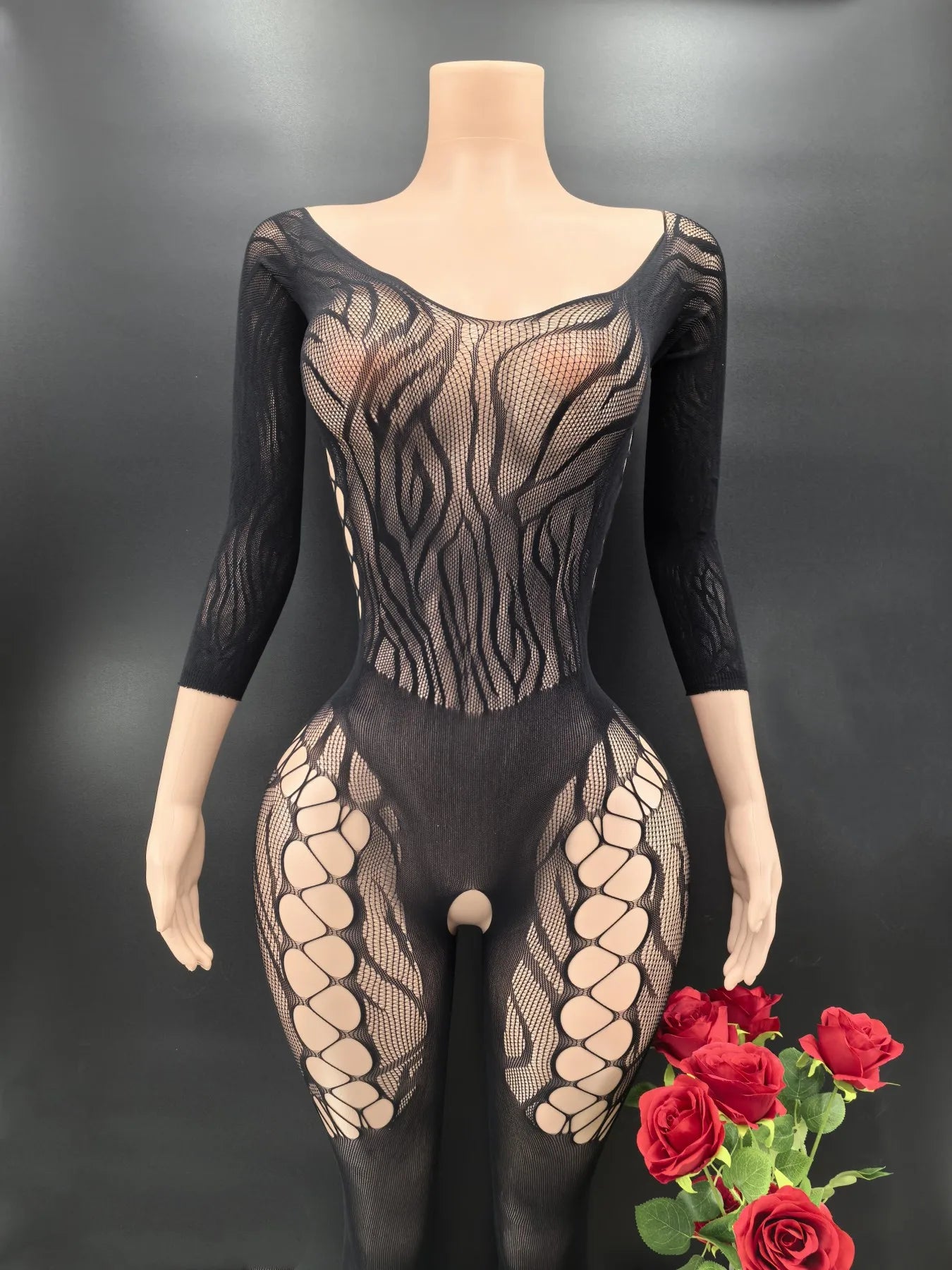 Black and beige fishnet bodysuit on a mannequin with red roses against a dark background