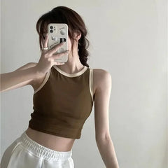 Person wearing a brown tank top and white pants taking a mirror selfie.