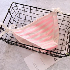 Pink and white striped towel draped over a black wire basket on a light gray surface.