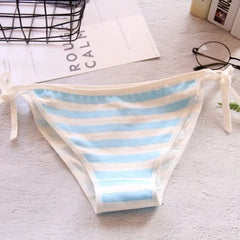 Striped bikini bottom on a light surface with books and glasses in the background