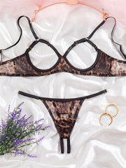Leopard print lingerie set on a white fabric background with flowers and rings.
