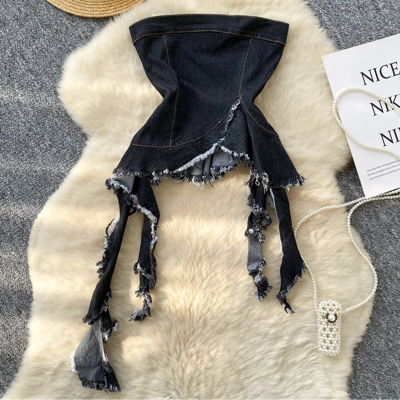 Black denim skirt with frayed edges on a textured surface with a hat and Nike tag.