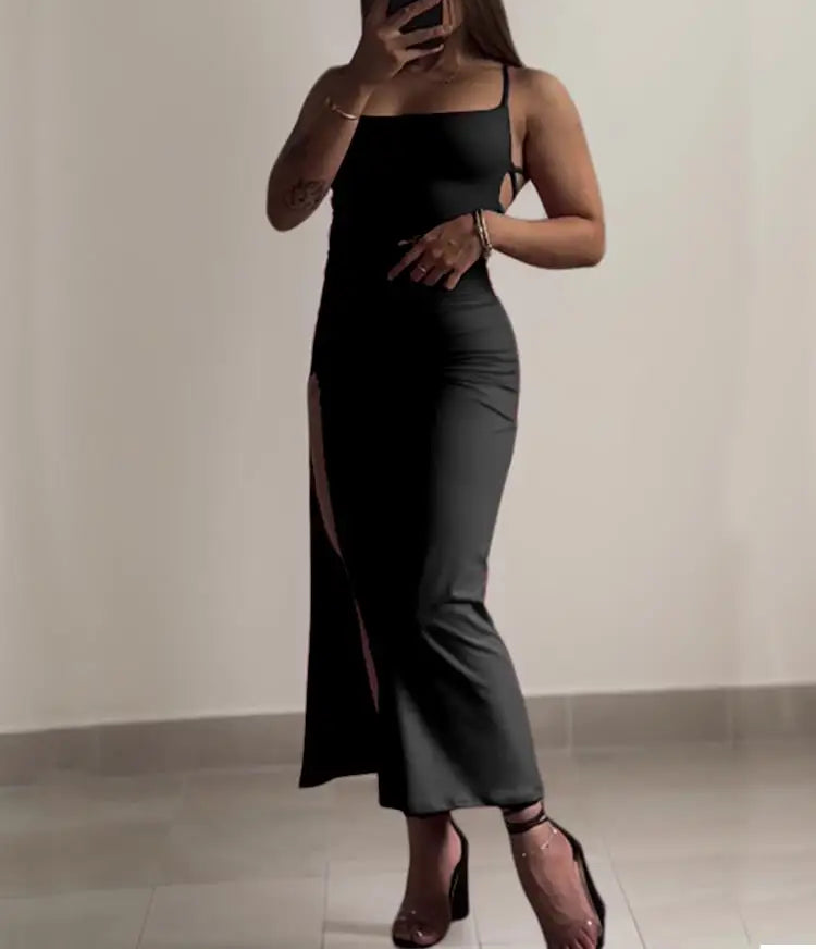 Person wearing a black dress with a slit, taking a mirror selfie.