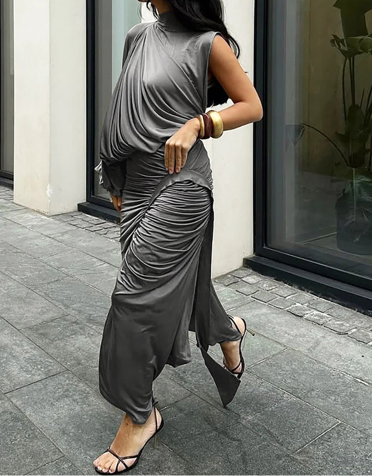Woman wearing a gray sleeveless top and pants walking outdoors.