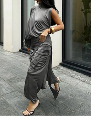Woman wearing a gray sleeveless top and pants walking outdoors.