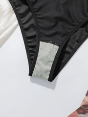 Close-up of a black bikini bottom with a contrasting light gray inner lining visible at the leg opening, laid flat on a white surface.