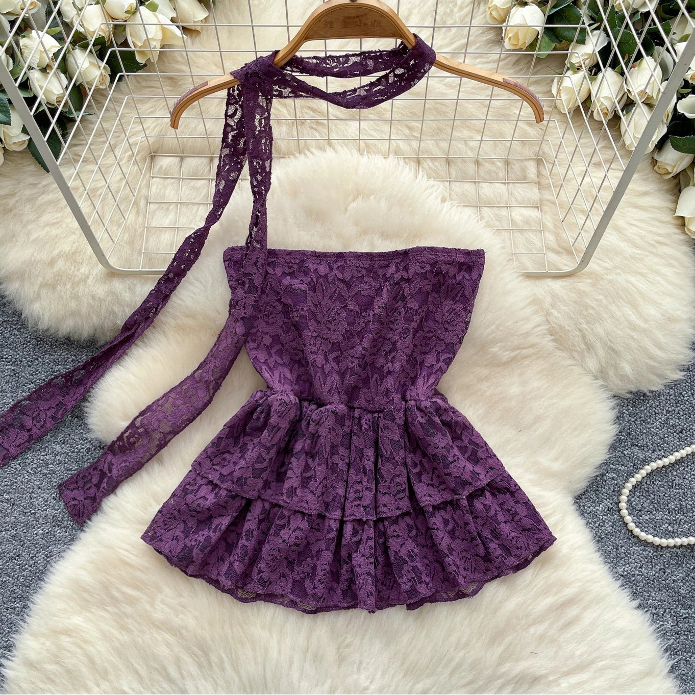 Purple lace dress on a hanger with floral decorations in the background
