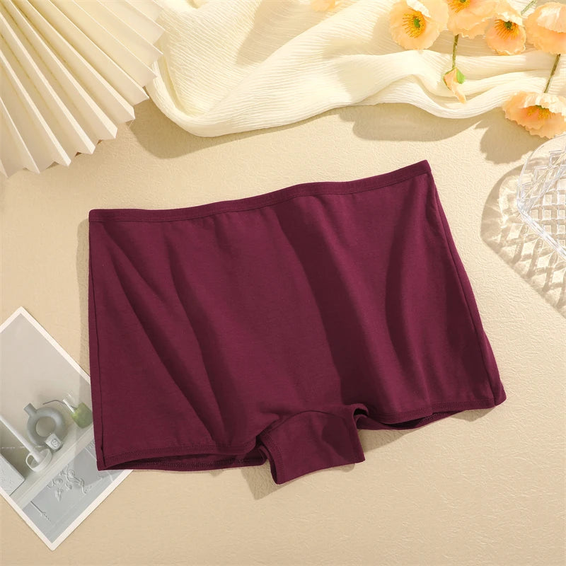 Maroon underwear on a beige surface with a white fan and flowers in the background