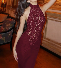 Woman in a burgundy lace dress posing in an elegant room.