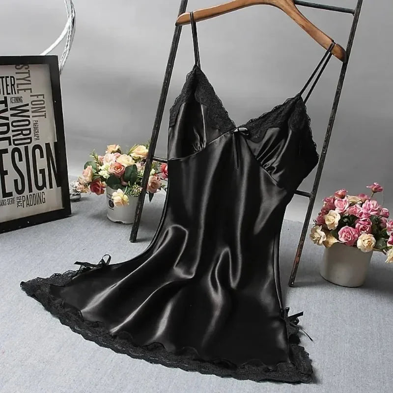 Black satin slip dress on a hanger with flowers and decor in the background