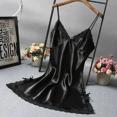 Black satin slip dress on a hanger with flowers and decor in the background