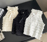 Three lace pet dresses in white, black, and cream on a black surface.