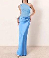 Woman wearing a light blue one-shoulder gown against a plain background