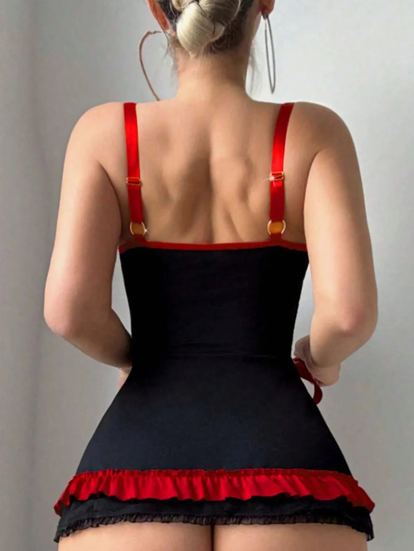 Person wearing a black and red dress with thin straps on a plain background