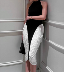 Woman wearing a black and white dress against a gray wall.