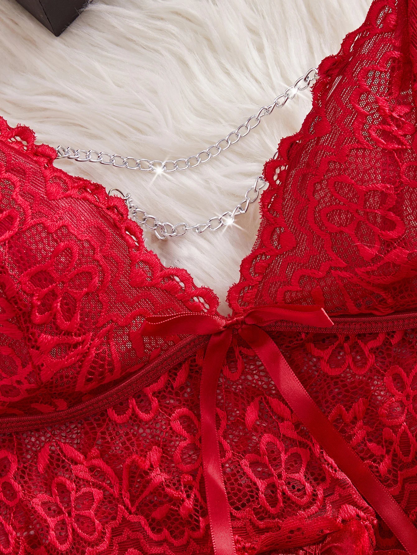 Red lace bra with a chain and ribbon on a white textured background