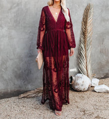 Woman wearing a burgundy lace dress against a textured wall with decorative elements.