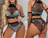 Woman wearing a black fishnet outfit with sparkles in a bedroom setting