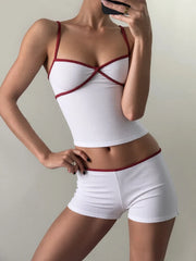 Person wearing a white and red sports bra and shorts set against a neutral background